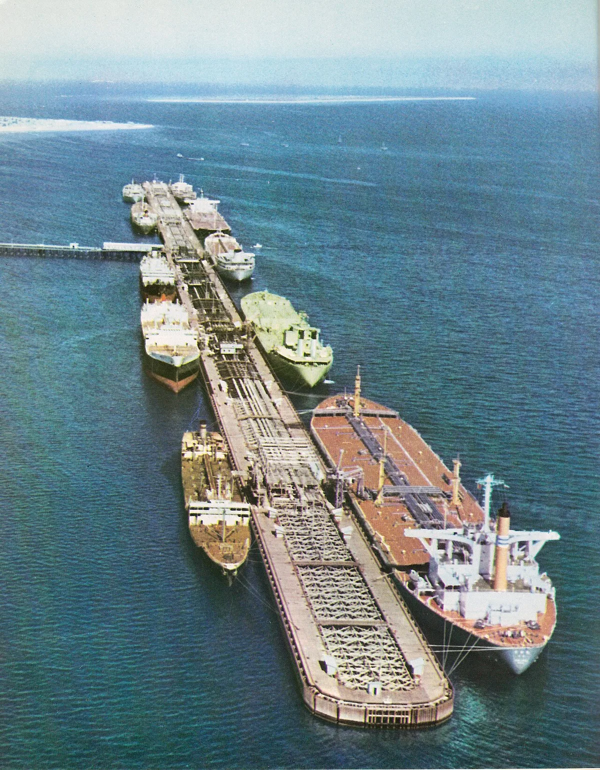 Oil tankers docked at an offshore oil loading terminal with pipelines and loading gear.