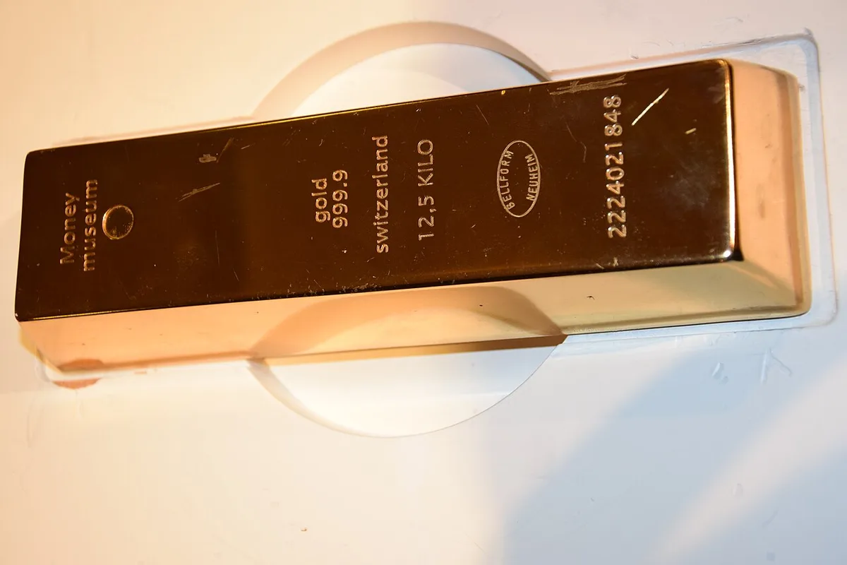 A gold bullion bar resting on a surface in a museum display.