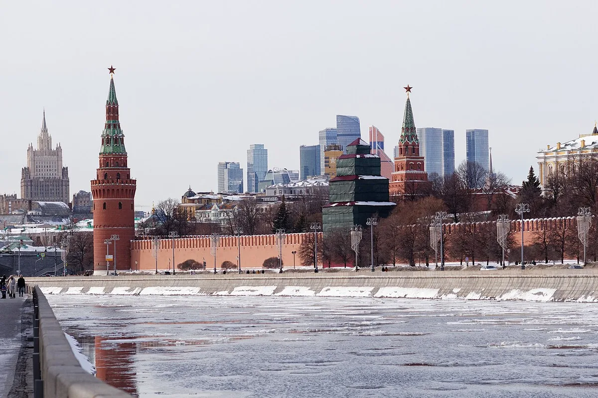 Moscow city skyline with high-rise towers behind the Kremlin under winter snow.