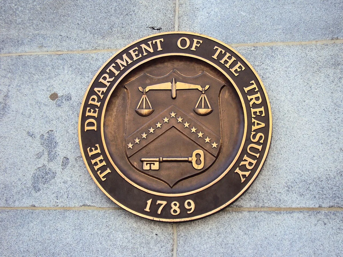 Bronze seal of the United States Department of the Treasury mounted on a stone building wall.